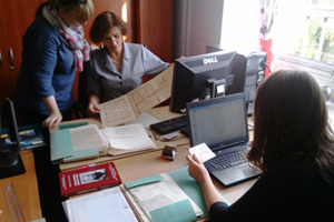 Zdjęcie, na którym widać trzy osoby pracującą przy opisywaniu archiwaliów - rękopisów prac naukowych i notatek wielkich archeologów.